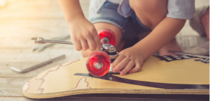 woman knelt over skateboard fixing bearings & wheels